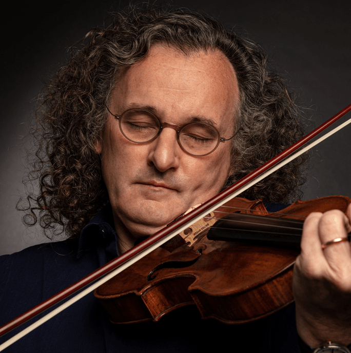 Close up of Martin Hayes. A man playing the violin in a black shirt with long hair wearing glasses