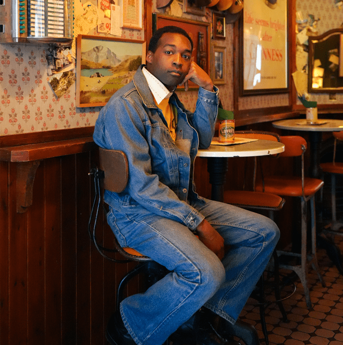 image of Jalen Ngonda in jeans and a denim jacket safe in a coffee shop